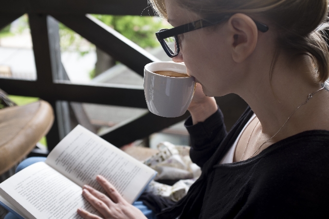 カフェでコーヒーを飲みながら読書をする女性